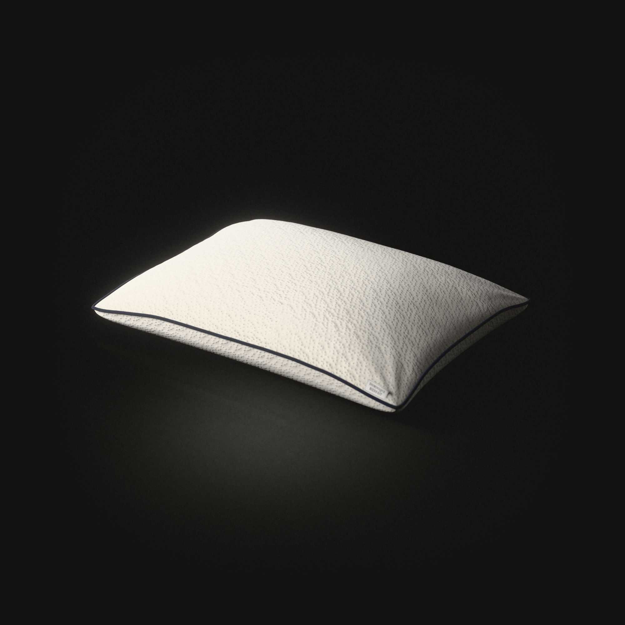 Un oreiller en latex crème sur un sol noir : un dôme bas et plein en tissu tricoté, creusé de petites alvéoles en rangées, un cordon bleu marine autour de sa couture, une petite étiquette blanche dans un coin.